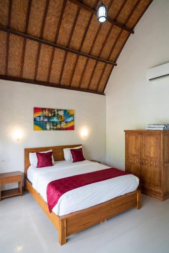 a bedroom with a large bed with red pillows at Sindhu Mesari Bungalow in Nusa Penida