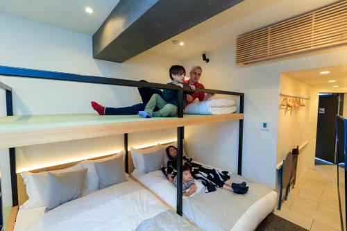 two children are laying on the bottom bunk of a bunk bed at Sakura Cross Hotel Ueno Iriya Annex in Tokyo
