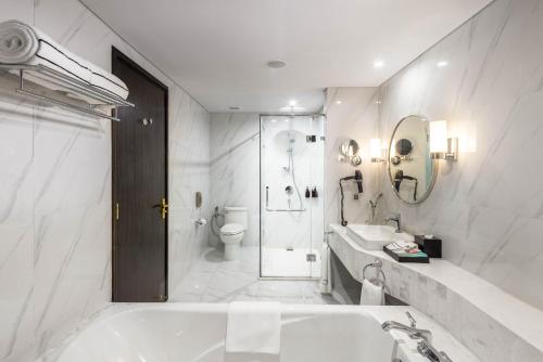 a white bathroom with a tub and a toilet at Vinpearl Ha Tinh, Affiliated by Melia in Ha Tinh