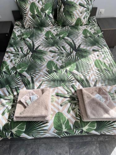 a bed with two towels on it with a green leafy bedspread at Hotel Rositsa in Veliko Tŭrnovo