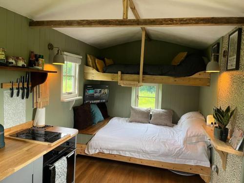 a bedroom with a bed and two bunk beds at Mountbatten Shepherds hut & Buckhurst Shepherds hut in Ashford