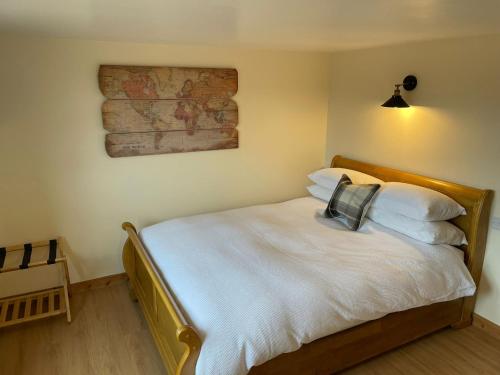 Schlafzimmer mit einem Bett mit weißer Bettwäsche und Kissen in der Unterkunft Little Buttercup Cottage in Brackley
