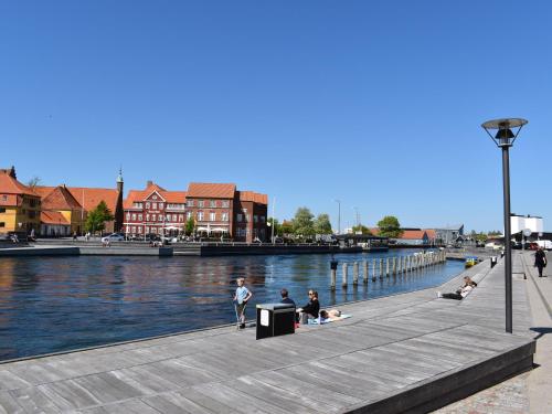 a group of people sitting on a dock next to the water at Kerteminde Byferie - Hyrdevej 83, 85B in Kerteminde