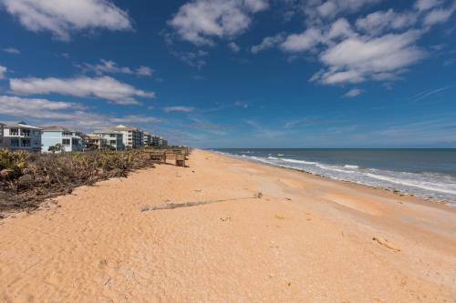 a sandy beach with houses and the ocean at SouthernVilla Ticket to Paradise in Palm Coast