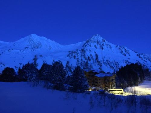 una montaña cubierta de nieve por la noche con un edificio en Nice Flat Le Varet Arcs 2000, en Arc 2000