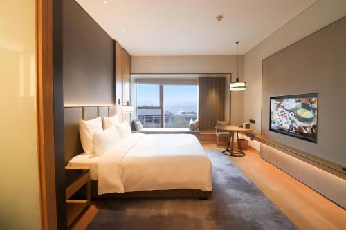 a bedroom with a large bed and a large window at Pullman Dali in Dali