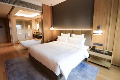 a bedroom with a large white bed and a bathroom at Pullman Dali in Dali