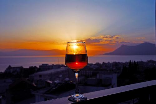 Mitho Hotel Spa في لوترا إديبسو: كوب من النبيذ يجلس على حافة مع غروب الشمس