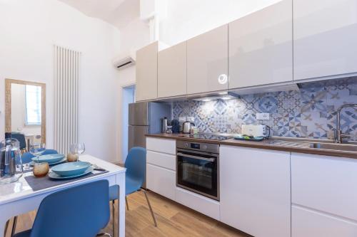 eine Küche mit weißen Schränken und einem Tisch mit blauen Stühlen in der Unterkunft CaseOspitali - Daimò, delizioso bilocale Fiera perfetto x5 in Bologna