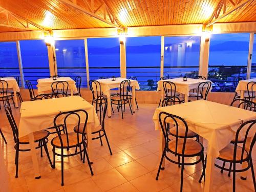 a room with tables and chairs with a view at Mitho Hotel Spa in Loutra Edipsou