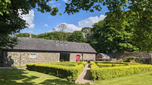 a stone house with a red door in a yard at The Old Bushmills Barn in Bushmills
