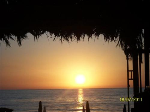 a sunset over the ocean with a straw umbrella at Residenza L'Antico Borgo Hotel in Filadelfia