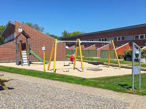a playground with yellow equipment in front of a brick building at 4 person holiday home on a holiday park in Hemmet in Hemmet