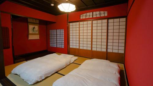 2 camas en una habitación con paredes y ventanas de color rojo en 古都とき Kototoki en Kanazawa