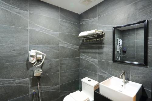 a bathroom with a toilet and a sink and a mirror at Yee Hotel Permas in Johor Bahru