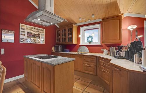 a kitchen with red walls and wooden cabinets at 4 Bedroom Awesome Home In Egernsund in Egernsund