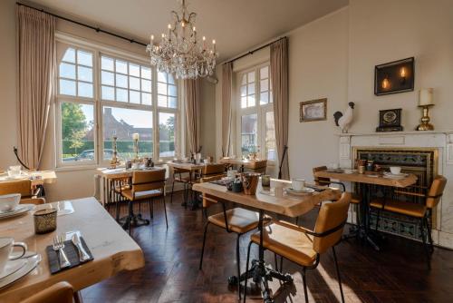 ein Restaurant mit Tischen, Stühlen und einem Kronleuchter in der Unterkunft Hotel Bonne Auberge (Adults Only) in De Haan