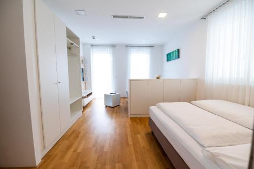1 dormitorio con 2 camas blancas y suelo de madera en sHome Hotel Graz - Self-Check-in & free parking, en Graz