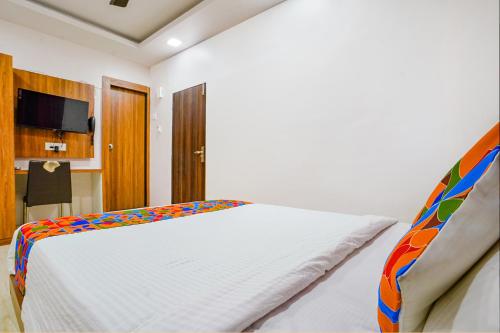 a bedroom with a white bed with a colorful blanket at FabExpress Diamond - Nr BKC in Mumbai