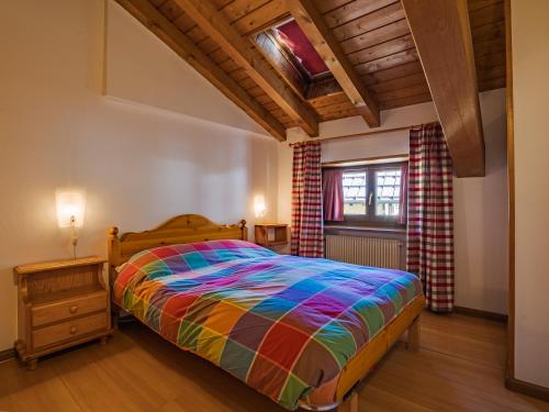a bedroom with a colorful bed and a window at Residenza 3-Tre in Madonna di Campiglio