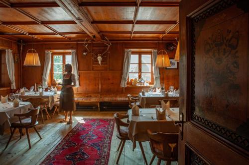 a woman standing in a dining room with tables at Hotel Zur Post in Alpbach
