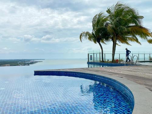 uma piscina com um homem ao lado do oceano em Seaview Suite SS Melaka by BetaStay em Malaca