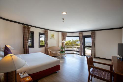 a hotel room with a bed and a living room at Imperial Phukaew Hill Resort in Khao Kho