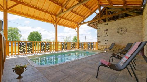 a swimming pool in the middle of a patio with a clock at Le Cabanot in Peyrusse-Grande