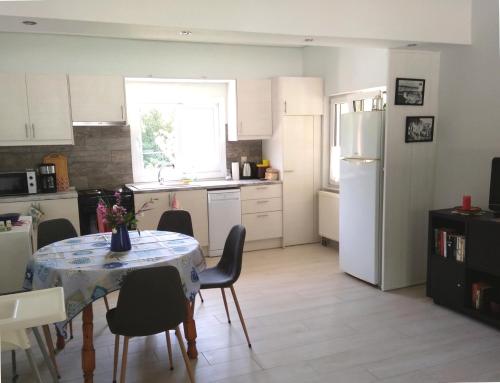 a kitchen with a table and chairs and a white refrigerator at Joleni Cottage in Keramies in Kefallonia