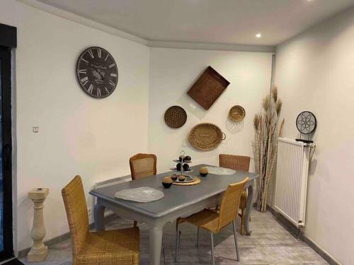 einen Esstisch mit Stühlen und eine Uhr an der Wand in der Unterkunft studio cosy 40m2 in Warlus