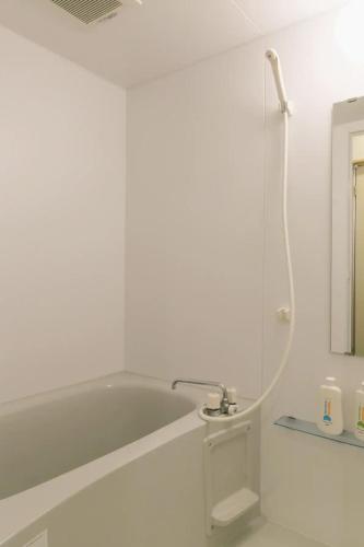 a white bathroom with a tub and a mirror at Reve K 301 in Naha