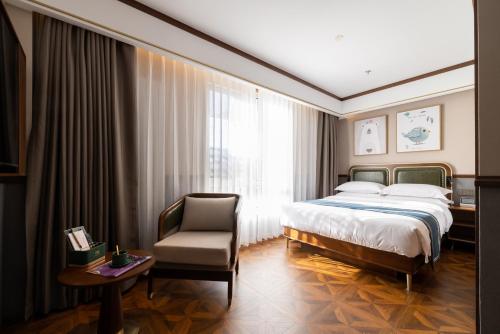 ein Hotelzimmer mit einem Bett und einem Stuhl in der Unterkunft 时光漫步S酒店(北京房山大学城广阳城地铁站店) in Peking