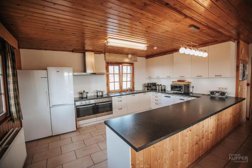 a kitchen with white appliances and a wooden ceiling at Le Gagnage 31 pers- Malmedy, rustique, vue, wellness in Malmedy