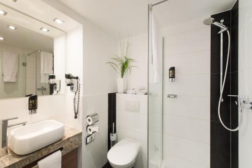 a bathroom with a shower, sink, and toilet at Hotel Mainstation in Frankfurt