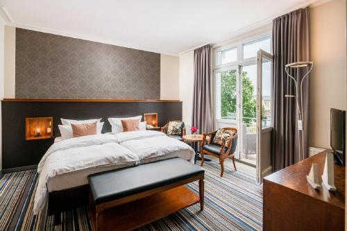 a hotel room with a large bed and a desk at Hotel Residenz Waldkrone Kühlungsborn in Kühlungsborn