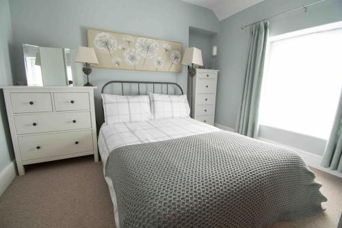 a bedroom with a bed and a dresser and a window at Tŷ Glas, Fishguard, Ideal for beach, coastal path and town! in Fishguard