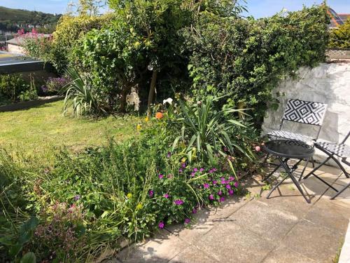 a garden with a chair and some flowers at Tŷ Glas, Fishguard, Ideal for beach, coastal path and town! in Fishguard
