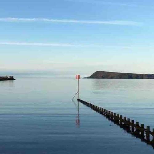 a sign in the middle of a body of water at Tŷ Glas, Fishguard, Ideal for beach, coastal path and town! in Fishguard