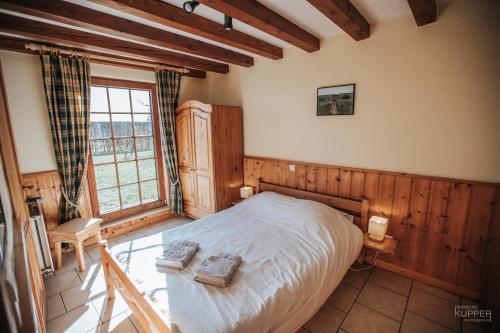 ein Schlafzimmer mit einem Bett in einem Zimmer mit Holzwänden in der Unterkunft Le Gagnage 31 pers- Malmedy, rustique, vue, wellness in Malmedy