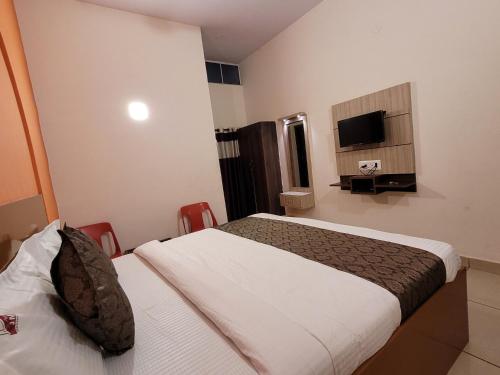 a hotel room with two beds and a tv at New Jaganmohana Comforts in Mysore