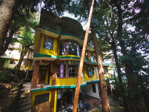a yellow building in the middle of trees at kailwood Guest House in McLeod Ganj