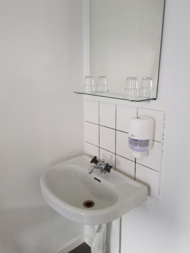 lavabo blanco en un baño blanco con gafas en Lilla Hotellet en Eskilstuna