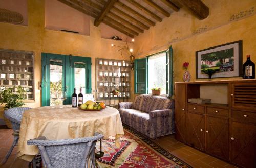 uma sala de estar com uma mesa, uma cadeira e garrafas de vinho em Agriturismo & Winery Il Bacio em Tavarnelle in Val di Pesa