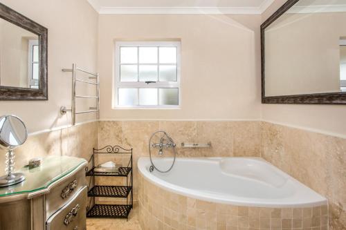 a bathroom with a tub and a sink and a mirror at Invergara in Cape Town