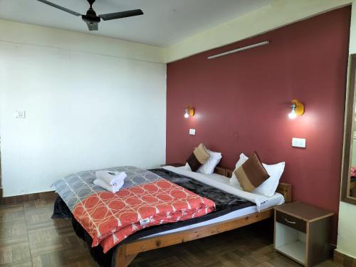 a bedroom with a bed with a red wall at kailwood Guest House in McLeod Ganj