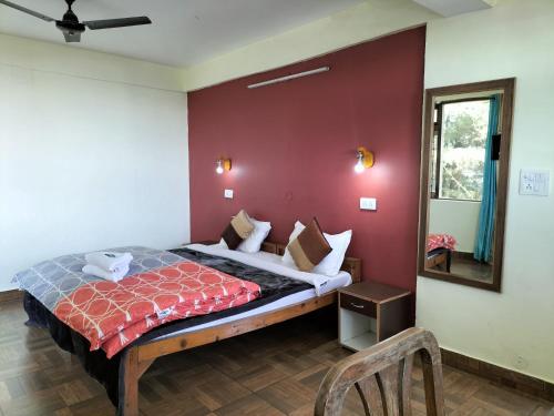 a bedroom with a bed with a red wall at kailwood Guest House in McLeod Ganj