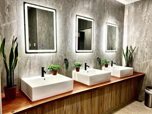 a bathroom with two sinks and two mirrors at Arena eSports Hotel @ Bugis Village in Singapore
