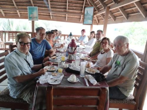a group of people sitting at a table eating food at ASSOUKA Eco-Village du lac Nokoué in Abomey-Calavi