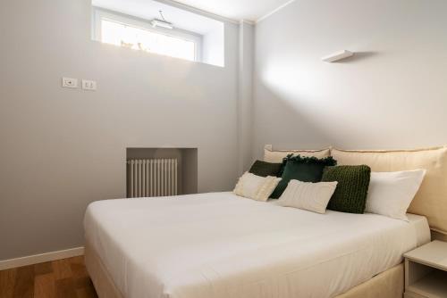 Un dormitorio con una cama blanca con almohadas verdes y blancas en easyhomes - Botta, en Milán