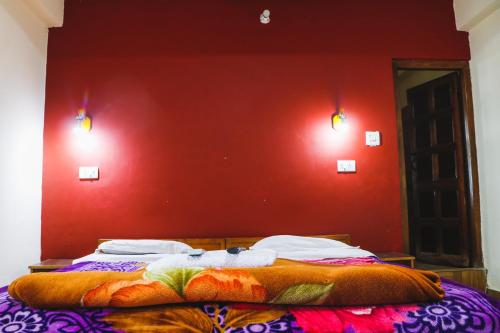 a bed in a room with a red wall at kailwood Guest House in McLeod Ganj